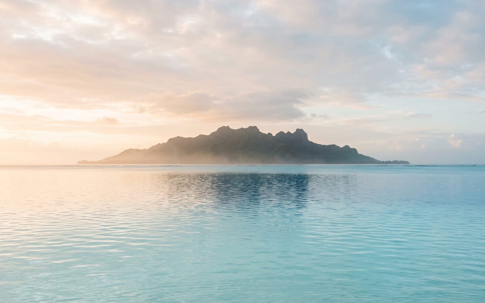 Une île à l'horizon, vue depuis un lagon calme : les archipels que dessert la boutique.